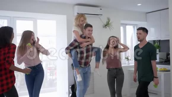 年轻人在家庭聚会上胡闹男孩和女孩在厨房里跳舞玩得很开心戴着塑料眼镜视频的预览图
