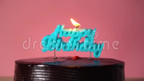 年轻人在粉红色背景上吹出蓝色生日快乐形状的蜡烛视频的预览图