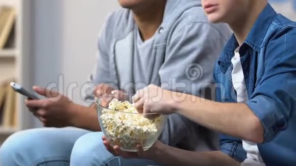 兴奋的青少年在有线电视上吃爆米花和看紧张的犯罪戏剧视频的预览图