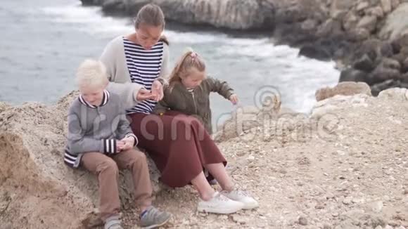 母亲带着孩子在海边的公园里散步视频的预览图