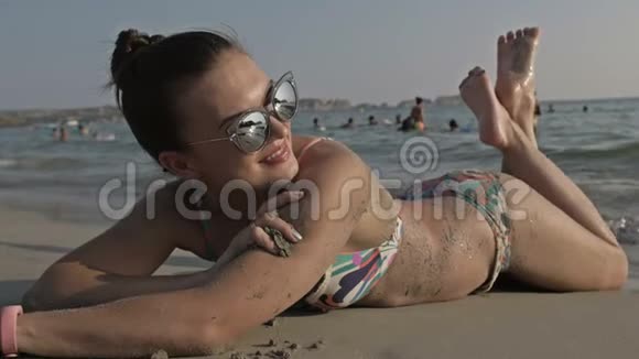 女人在海滩上晒日光浴展示双腿与比基尼海滩的身体和美丽的健康皮肤女性度假模特视频的预览图