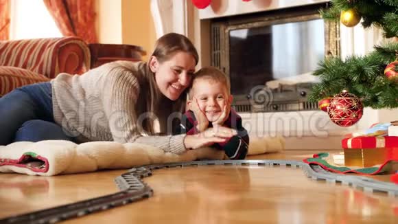 快乐微笑的家庭躺在客厅的地板上看着骑玩具火车的4k视频儿童接受礼物视频的预览图