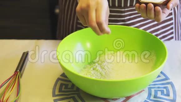 在家庭厨房的绿色碗里一只雌性的手在面粉中加入盐烹饪煎饼视频的预览图