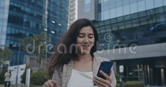 有魅力的女人在街上散步时使用手机在佳能相机上拍摄12位颜色深度视频的预览图