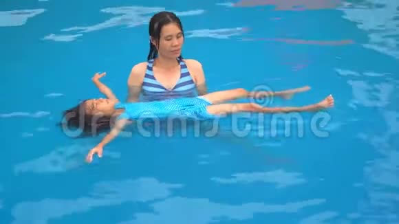 家庭孩子有趣的概念妈妈在夏天训练女儿在游泳池游泳视频的预览图