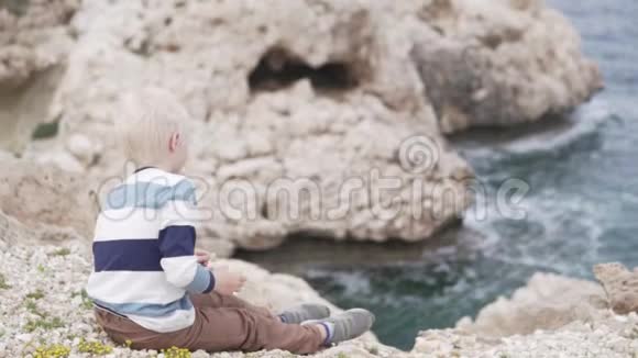 一个英俊的金发男孩在海上扔石头视频的预览图