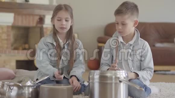 肖像可爱可爱的兄妹双人演奏音乐家用大勺子敲打锅碗瓢盆大笑视频的预览图