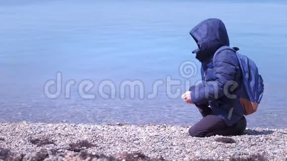 令人认不出的少年在海上的岩石海滩上喂养鸽子视频的预览图