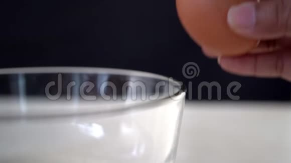 厨师手把一个鸡蛋打碎到玻璃碗里特写宏观镜头视频的预览图