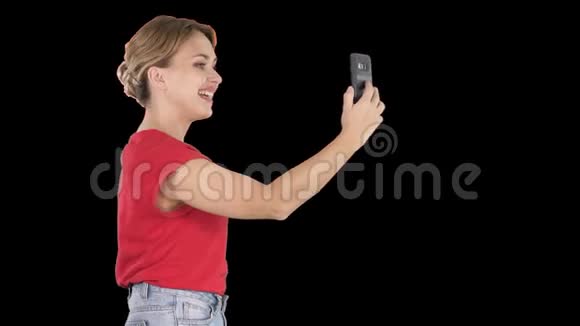 美丽的年轻女子走着拿着智能手机拍照和自拍阿尔法频道视频的预览图
