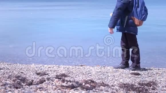 不可辨认的男孩在冬天在海上的岩石海滩喂养鸽子视频的预览图
