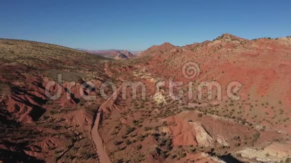泥土路穿过沙漠有红沙和岩石团视频的预览图