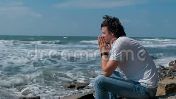 心烦意乱的年轻人坐在海滩上看着海浪视频的预览图
