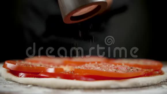 厨师在黑色的背景上为披萨撒盐和香料视频的预览图
