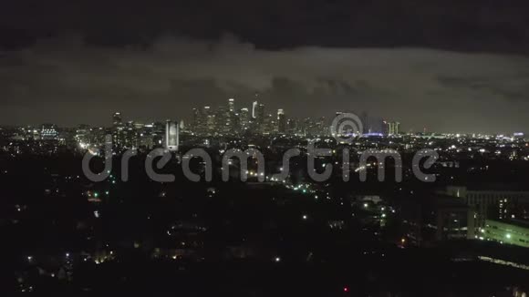 空中夜晚在黑暗的好莱坞洛杉矶上空市中心和城市灯光笼罩着云层视频的预览图