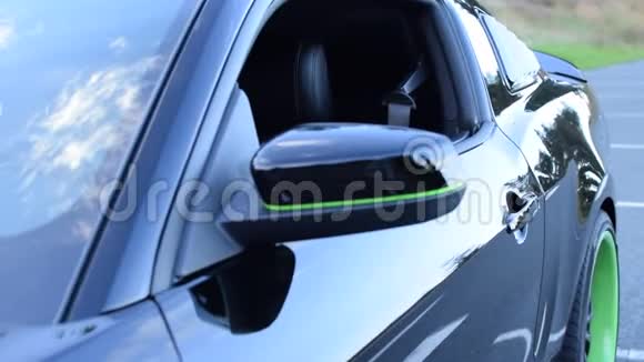 黑色绿色的福特野马汽车从车窗上关上日光下森林街道视频的预览图