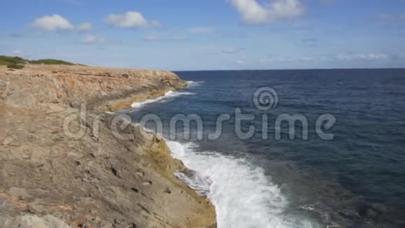 西班牙马洛卡热带岛屿的岩石海岸的波浪破碎晴天蓝天波浪海洋夏天视频的预览图