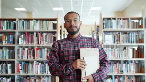 非裔美国学生带着书在大学图书馆散步的肖像视频的预览图