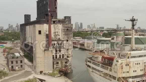 灰蒙蒙的一天在纽约市码头的锈迹斑斑的旧货船和旧仓库上空视频的预览图