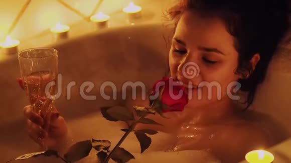年轻女孩在浴室里放松手里拿着玫瑰和一杯葡萄酒视频的预览图