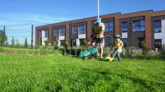 快乐的小男孩推玩具割草机而园丁人割草万向节运动视频的预览图