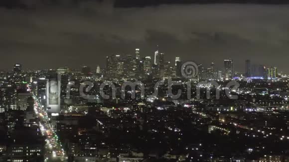 星光在黑暗的好莱坞洛杉矶在威尔郡大道上的夜景在市中心和城市灯光下有云视频的预览图