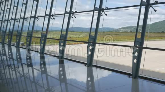 现代化的机场透过窗户看到美丽的跑道和客运码头山脉背景视频的预览图
