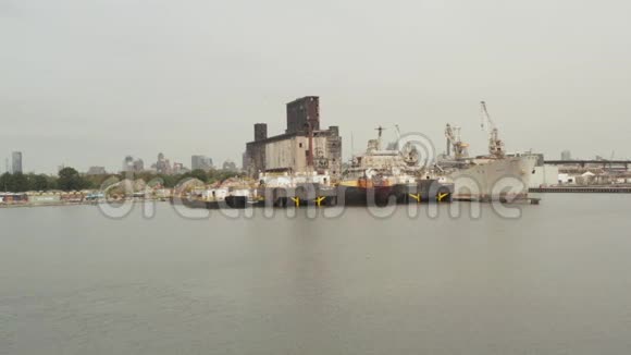 灰蒙蒙的一天在纽约市码头的锈迹斑斑的旧货船和旧仓库上空视频的预览图
