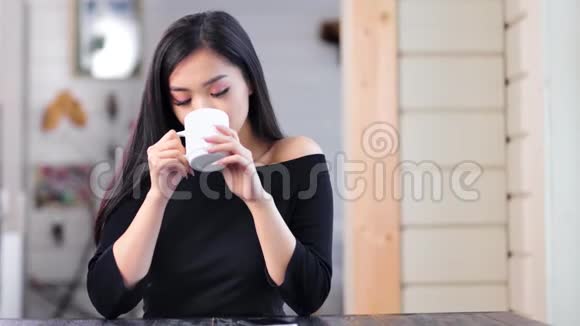 优雅可爱的亚洲小女孩在家里坐在桌子旁喝热饮料视频的预览图