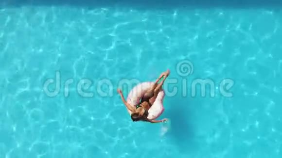 泳池里的女孩在粉红色的充气甜甜圈上游泳视频的预览图