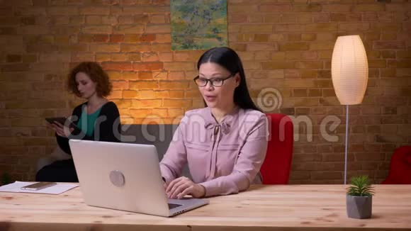 成年亚洲女商人在办公室内使用笔记本电脑的特写镜头三个员工打视频电话视频的预览图