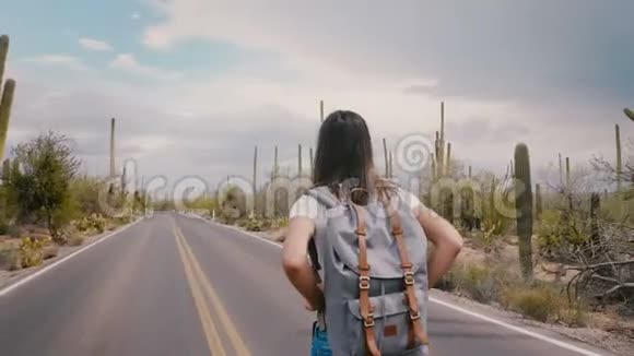 慢动作美丽的年轻快乐的旅游妇女走在沙漠国家公园的道路上手臂张开在暴风雨前视频的预览图