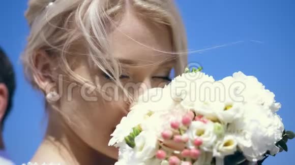 肖像特写美丽的金发新娘享受她的婚礼花束的香味她的金发卷发视频的预览图