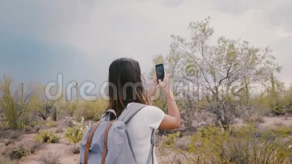 慢镜头在年轻快乐微笑的旅游妇女周围移动在仙人掌沙漠国家公园拍照视频的预览图