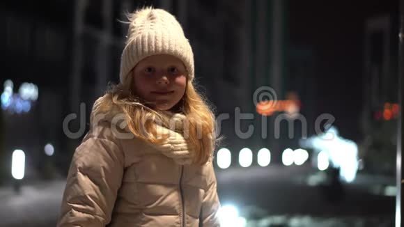 冬天一个金发女孩在圣诞节装饰的街道上美丽的肖像视频的预览图