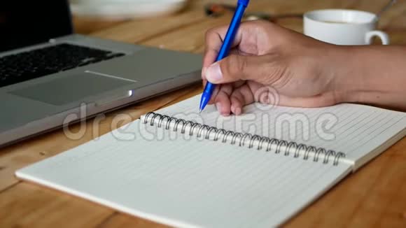 一个男人有选择性地把注意力集中在一张桌子上的白纸上上面有一杯咖啡和一本电脑笔记本视频的预览图