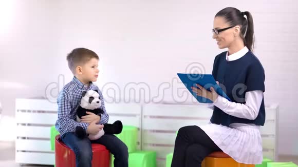 微笑女专业儿童心理学家与小男孩交谈中长镜头视频的预览图