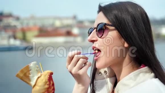 戴墨镜的可爱的微笑女人吃着冰淇淋走在河堤上享受着分手的乐趣视频的预览图
