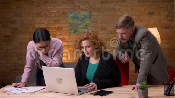 在笔记本电脑上工作的年轻女商人的特写镜头与两位同事一起快乐并庆祝成功视频的预览图