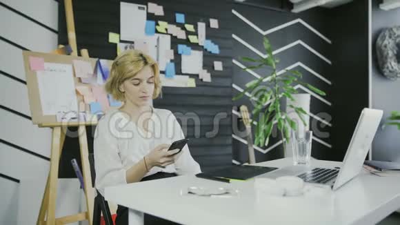 年轻的休闲女士坐在办公桌前用笔记本电脑接电话打电话视频的预览图