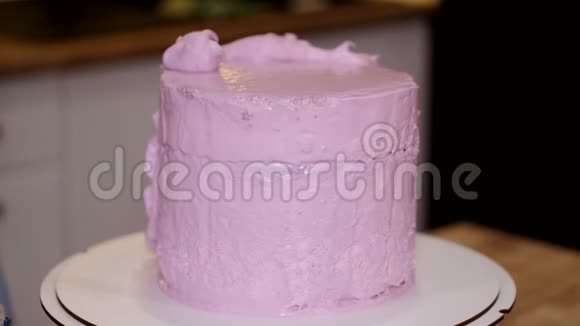 一个女面包师正在蛋糕上抹粉红色奶油视频的预览图