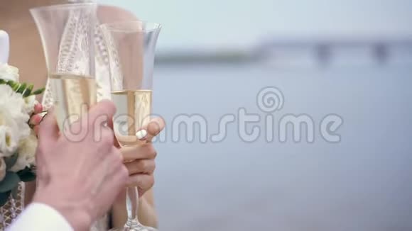 特写新婚夫妇正捧着香槟酒杯在蓝天的背景下春天阳光明媚视频的预览图
