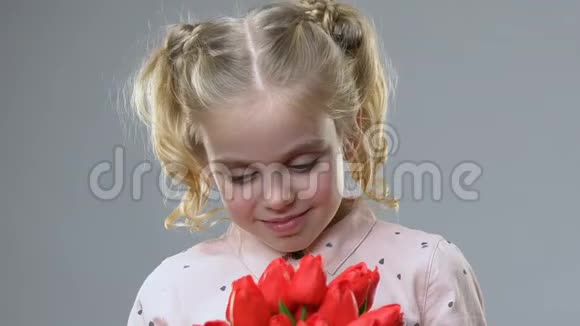 可爱的女孩闻着鲜花享受着春天的时光女性的气质和温柔视频的预览图