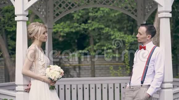 一对年轻漂亮的夫妇正站在露台上彼此相对互相递上一束结婚花束视频的预览图