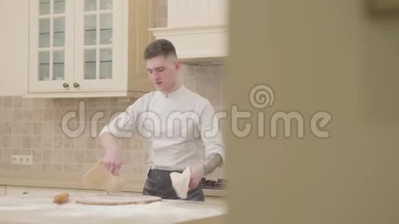 有魅力的家伙在家里的厨房里旋转和扔两盘比萨饼面团专业披萨店视频的预览图