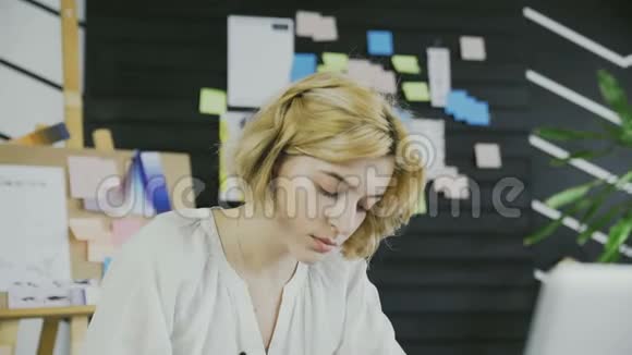 年轻女子在办公室的笔记本上做笔记视频的预览图