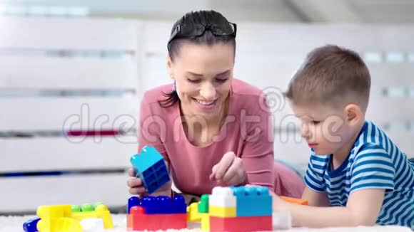 可爱的快乐的年轻妈妈和小可爱的儿子在家玩建构游戏视频的预览图