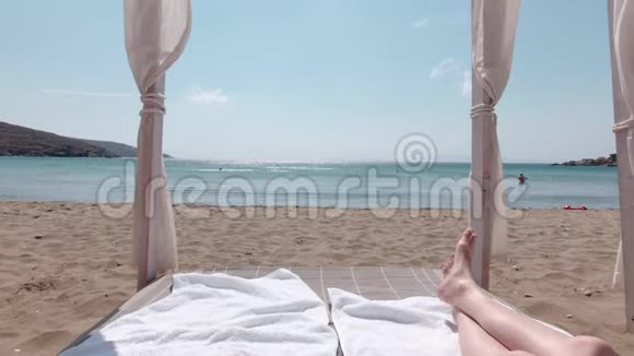 在阳光明媚的一天男人在海滩床上放松阿吉欧斯罗马诺斯希腊视频的预览图