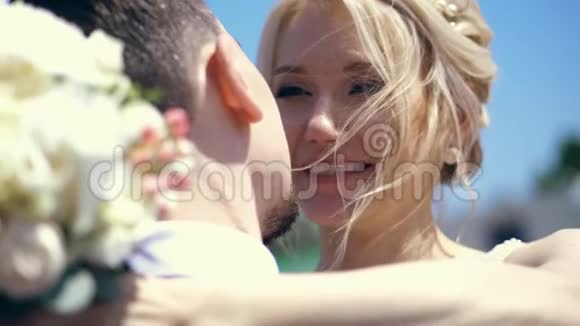 特写肖像新娘拥抱新郎手拿着一束花躺在新郎的肩膀上婚礼视频的预览图