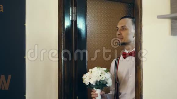 在门口年轻人进来了新郎戴着红色的蝴蝶结带着一束花他看着新娘视频的预览图